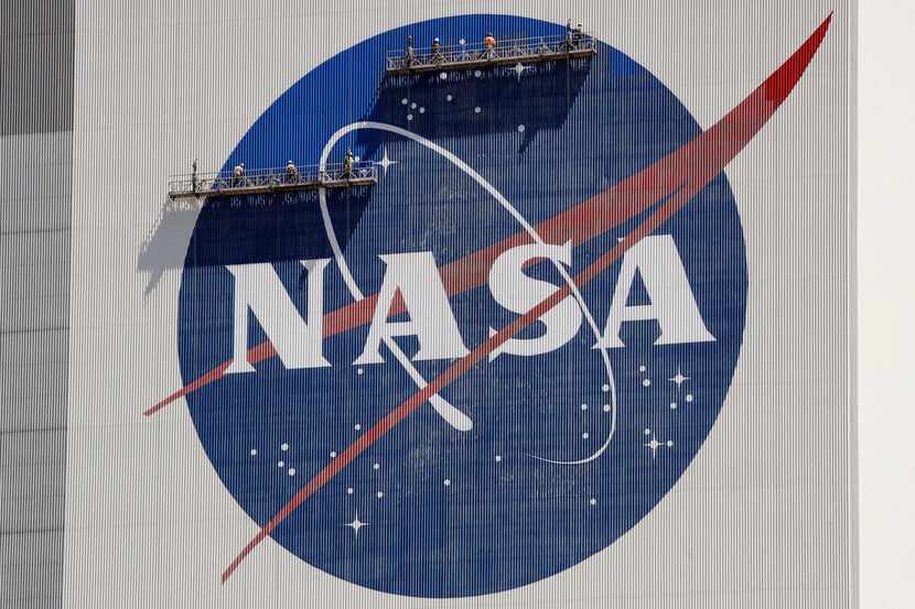 ARCHIVO - Trabajadores en andamios repintan el logo de la NASA en el Centro Espacial...