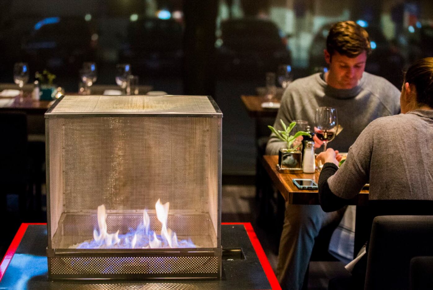 An indoor fire pit burns beside diners.