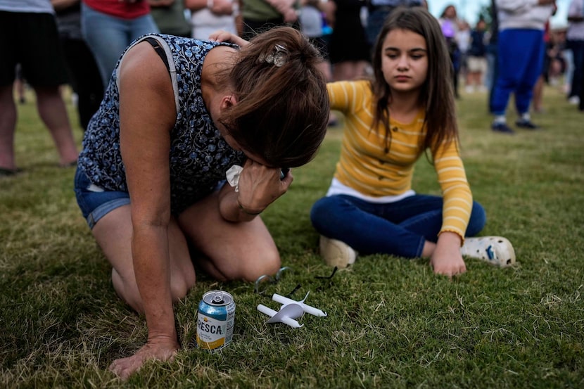 Brandy Rickaba and her daughter Emilie pray during a candlelight vigil for the slain...