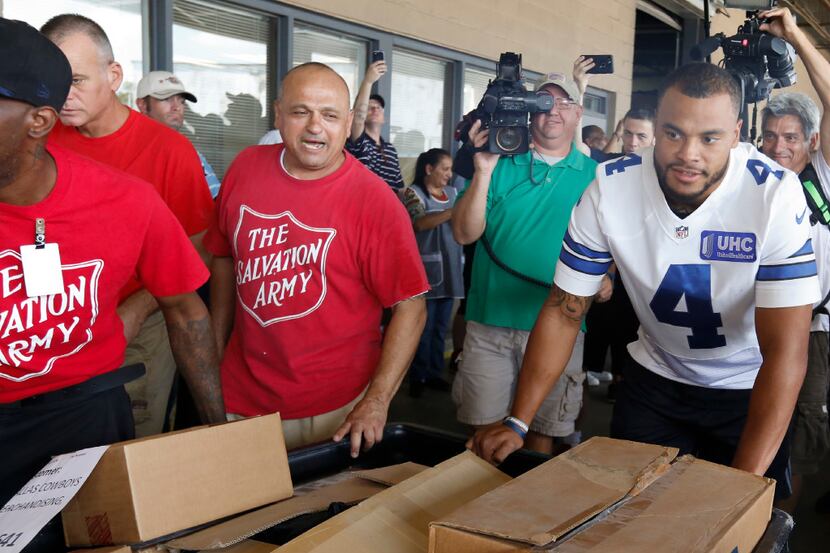 Dallas Cowboys quarterback Dak Prescott, #4, and The Salvation Army personnel move a cart of...