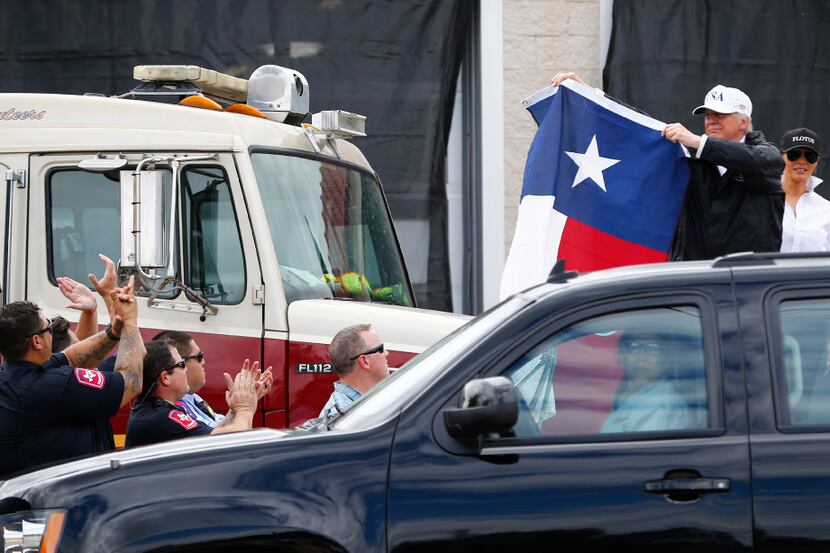 President Donald Trump holds up a Texas flag after attending a briefing from federal, state...