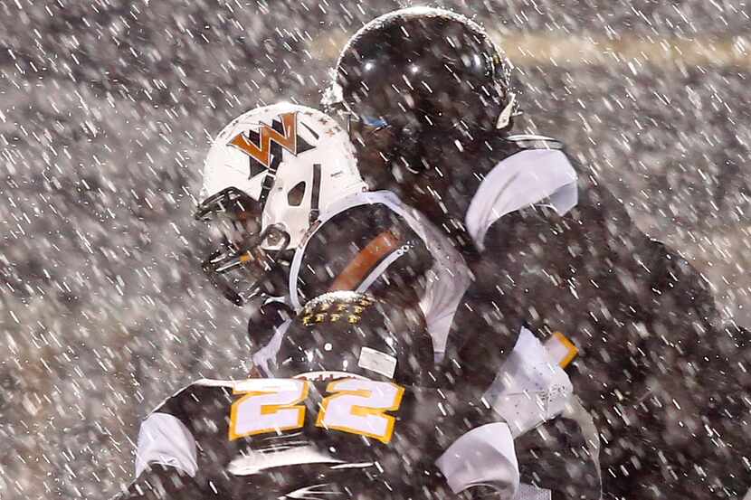 Rain pours down as West Mesquite's Curtis Williams (6) tries to break away from Forney's...