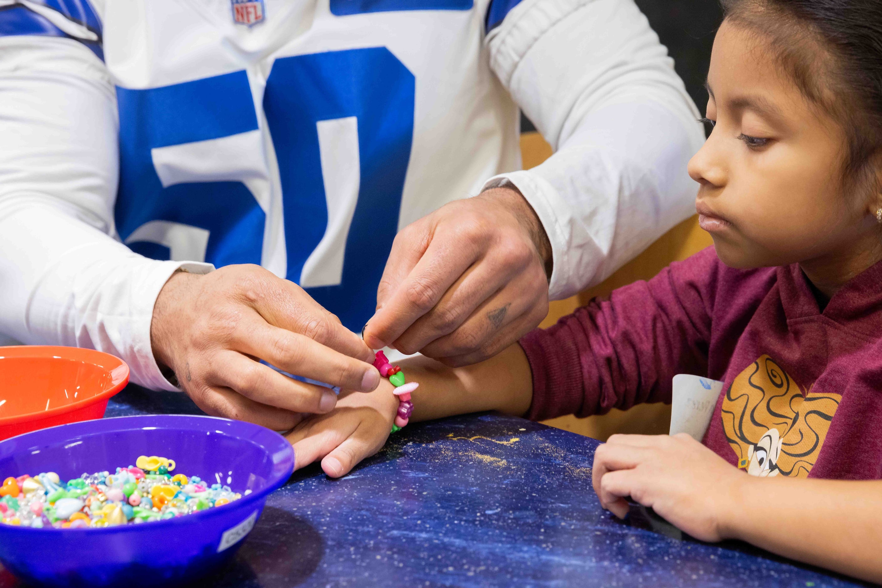 Dallas Cowboys linebacker Eric Kendricks (50) ties a friendship bracelet on Venus Garcia, 7,...