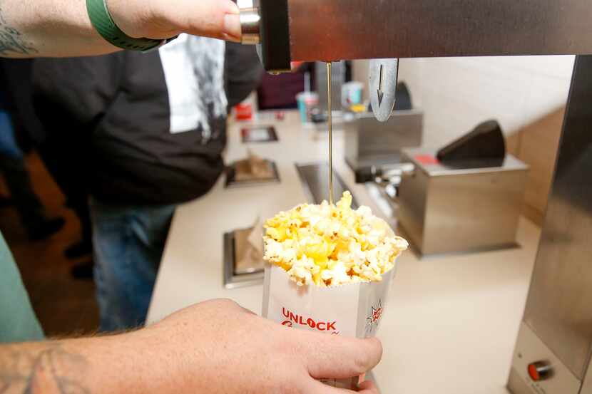 A movie goer butters his popcorn at a newly remodeled Cinemark theater at the corner of Coit...