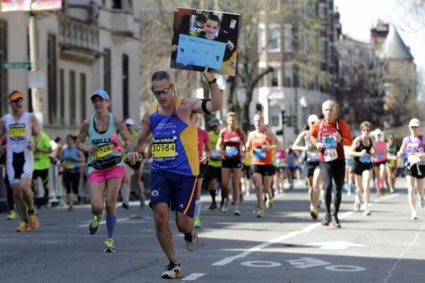 
Joseph Torpy of Boston hoists a picture of 8-year-old Martin Richard, one of three people...