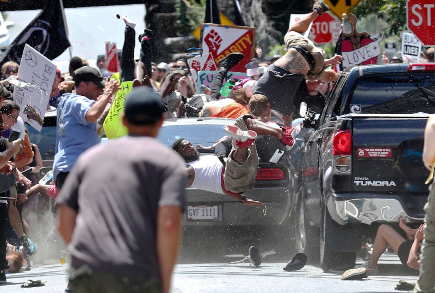 People fly into the air as a vehicle drives into a group of protesters demonstrating against...