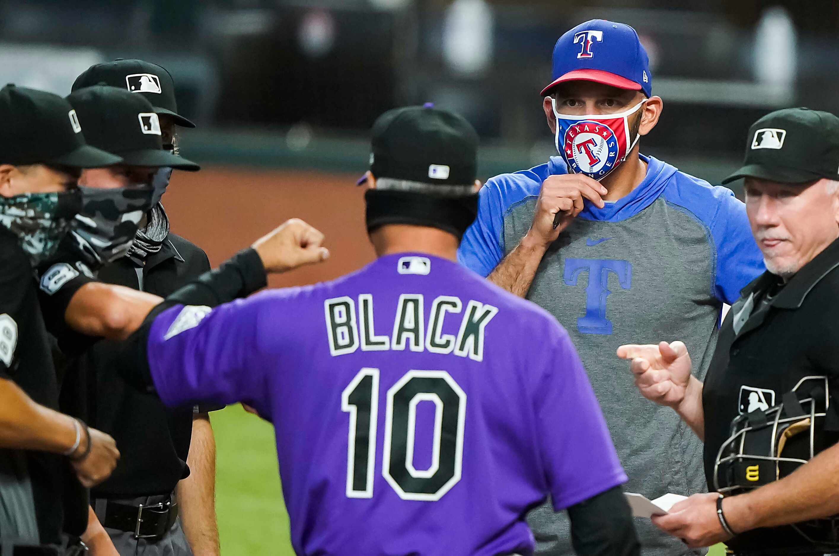 Texas Rangers manager Chris Woodward adjusts his face mask as he meets with Colorado Rockies...