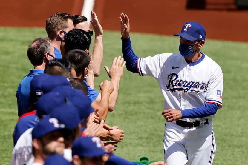 Texas Rangers manager Chris Woodward receives high-fives from his players during the team...