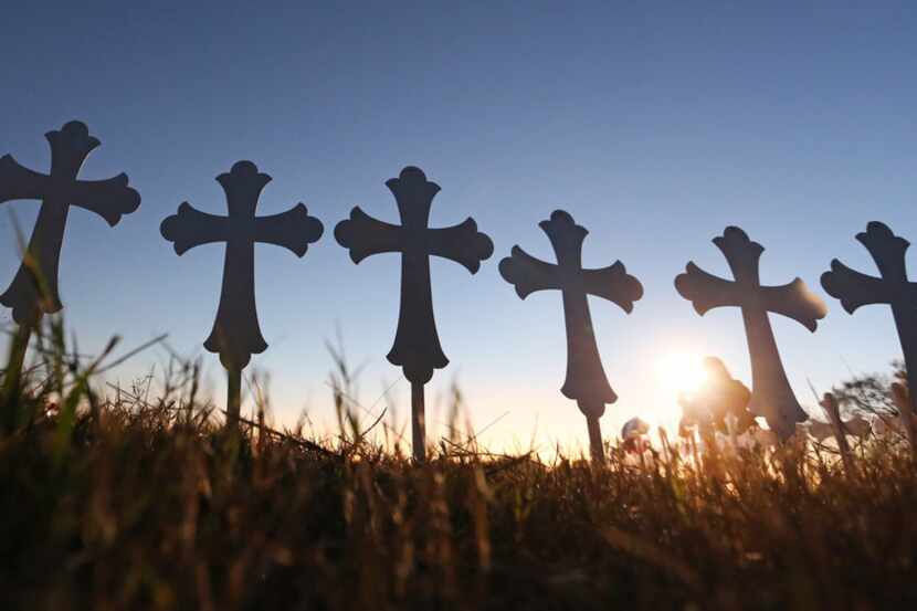 Some of the 26 crosses placed in a field  silhouetted in the evening light in Sutherland...