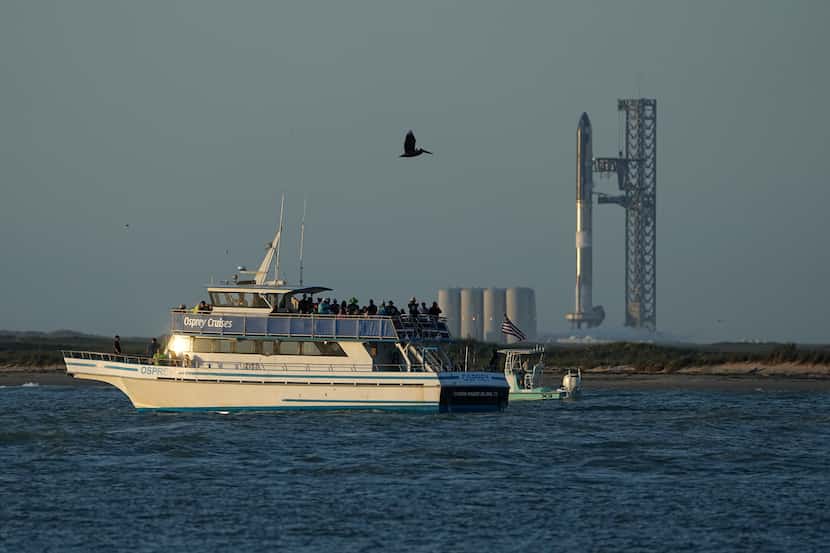 A boater passes SpaceX's Starship, the world's biggest and most powerful rocket, as it...