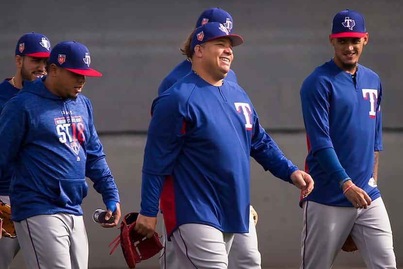 Texas Rangers pitcher Bartolo Colon (center) laughs with teammates as they take the field...