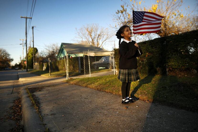 
Brianna Machado, 5, waves her U.S., flag to passing cars in the La Bajada neighborhood in...