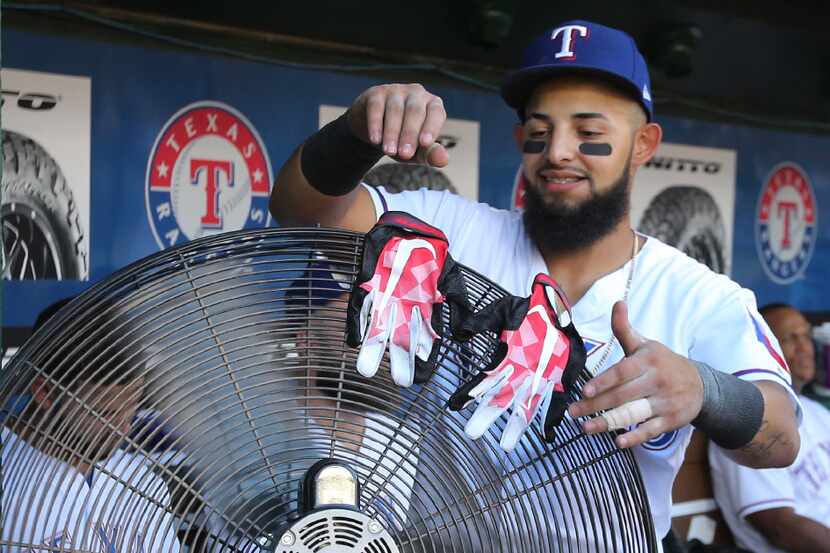 Texas Rangers second baseman Rougned Odor (12) tries to dry out his batting gloves on an...