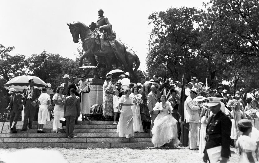 Dressed for a celebratory occasion, members of a crowd mill about the newly unveiled statue...