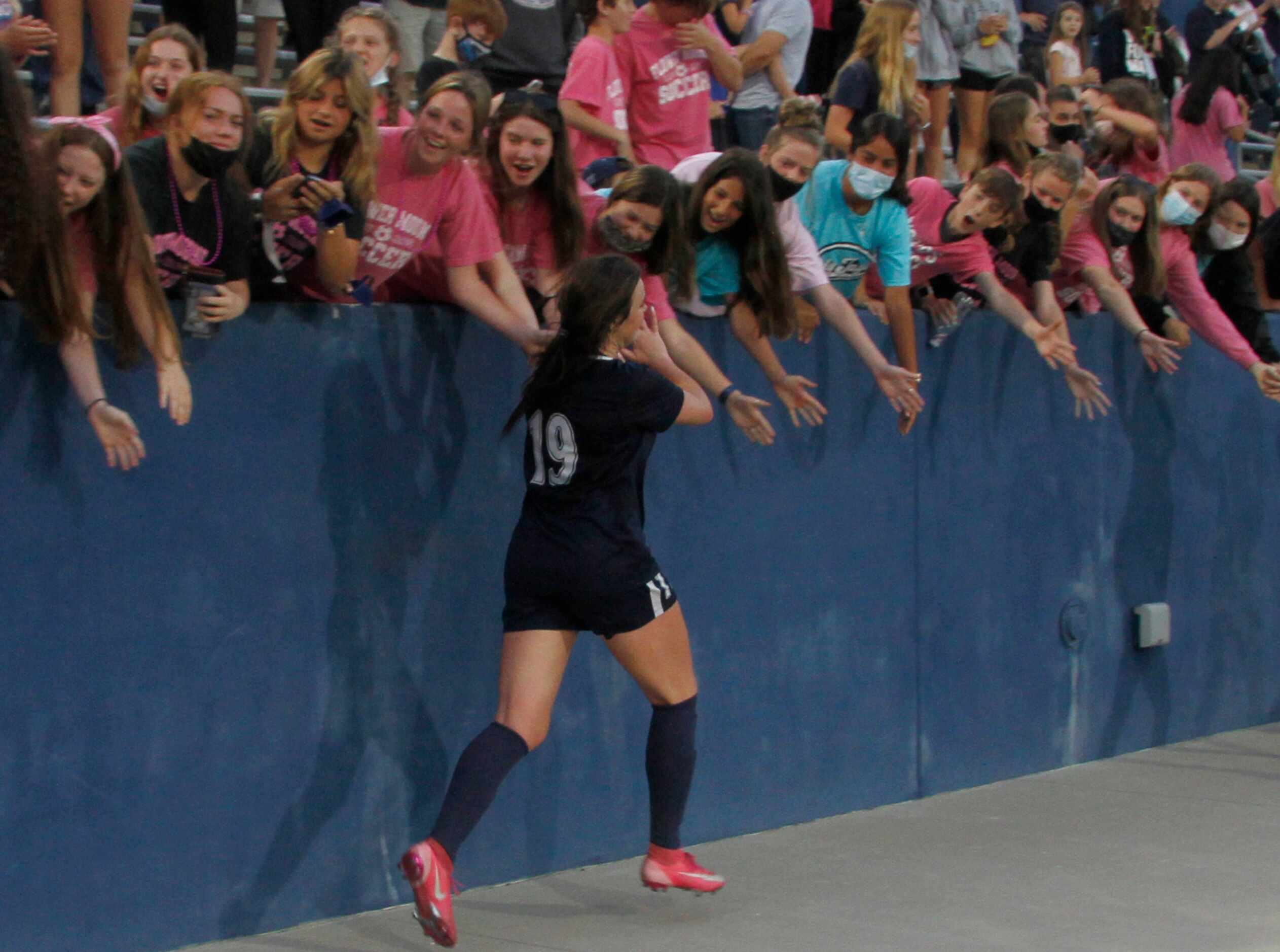 Flower Mound's Riley Baker (19) jogs past fans filling the school's student section...