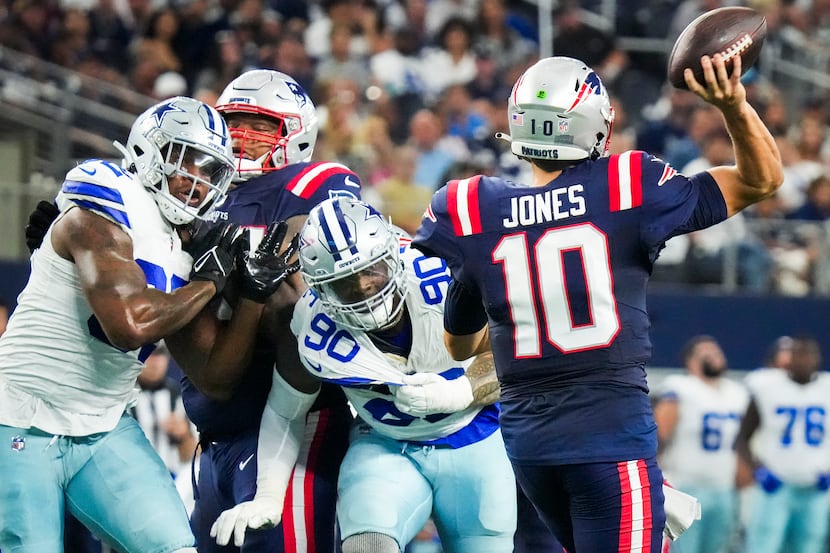 New England Patriots quarterback Mac Jones (10) throws a pass under pressure from Dallas...