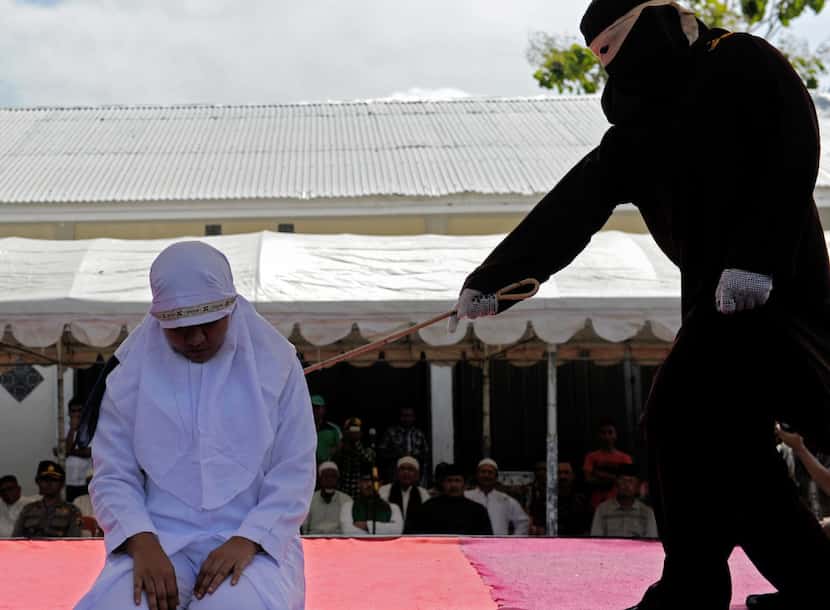 Sharia law officers punish a woman accused of cheating on her husband by whipping her on...