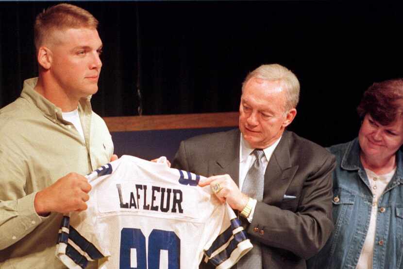 Dallas Cowboys owner Jerry Jones, center, helps the Cowboys' first draft pick, Louisiana...