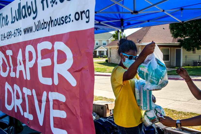 Volunteer Harmony Cornelius (center), 12, prepares diaper packages for families visiting a...