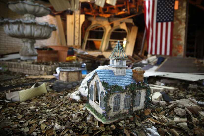 A small replica of a church sits amid the rubble left behind on the front sidewalk of a...