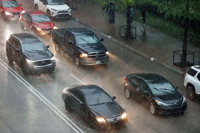 Cars drive along Commerce Street as rain falls during a severe warned thunderstorm in...