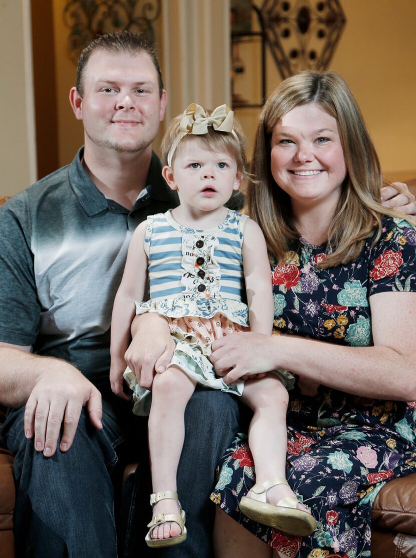 Marshall and Jessica Hitt and their daughter, Olivia, 2, sit for a portrait at their home in...