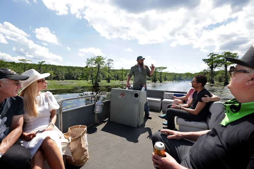 Chaz Warren, center, explains the finer points of Caddo Lake on a pontoon headed toward...