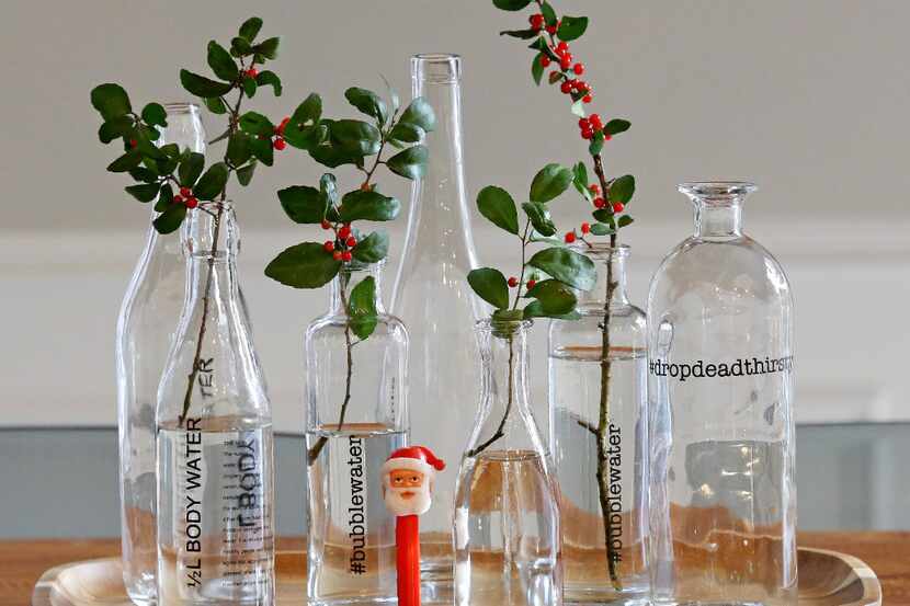 A grouping of glass bottles gets a holiday look with a  a few snippings from the yard....