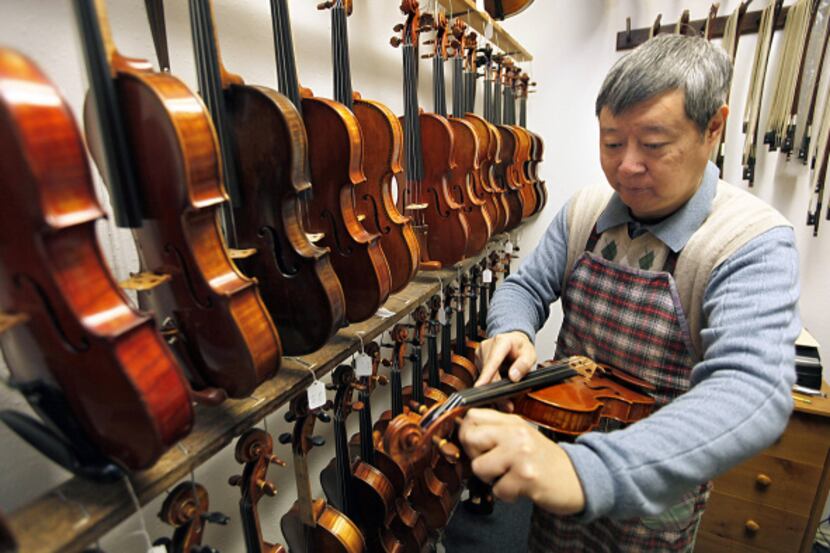 Kelin Zhang, 50, of Frisco tunes a violin at his shop.
