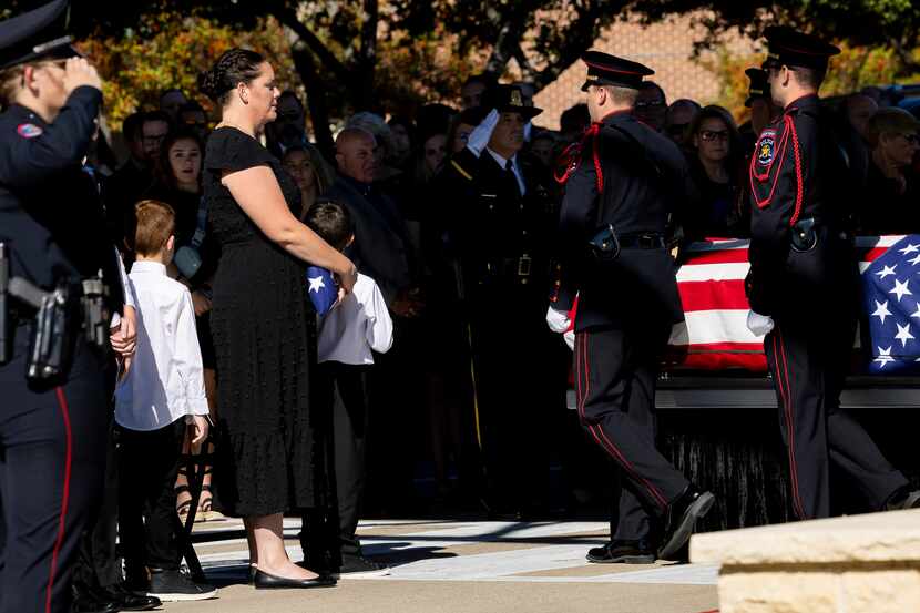 Cristl Nothem and her family watch as pall bearers take the casket of her husband Carrollton...