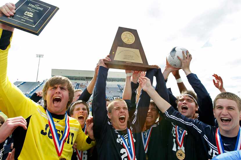 Dallas Jesuit players celebrate with the UIL Class 5A boys soccer championship trophy after...