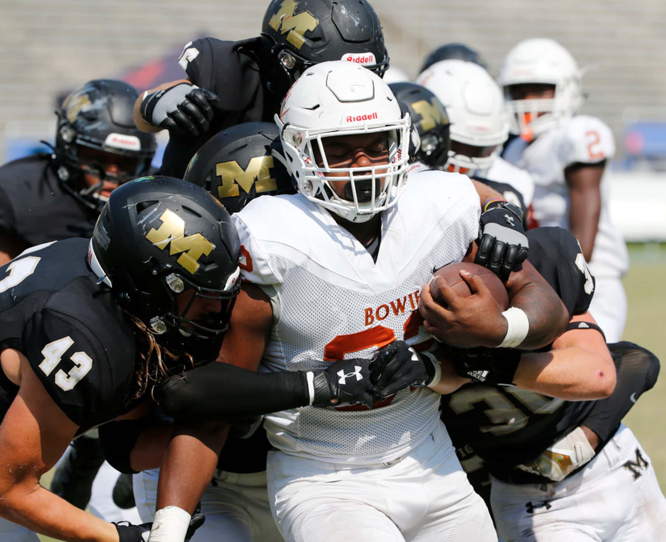 Mansfield defender Tyler Cole (43) and others gang tackle Arlington Bowie's Marsaillus Sims...