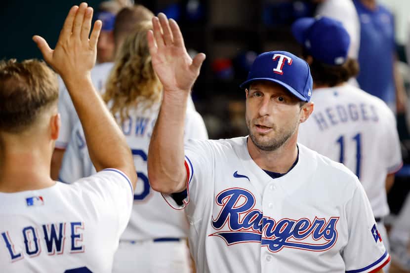 Texas Rangers starting pitcher Max Scherzer (31) delivers and receives fist bumps and...