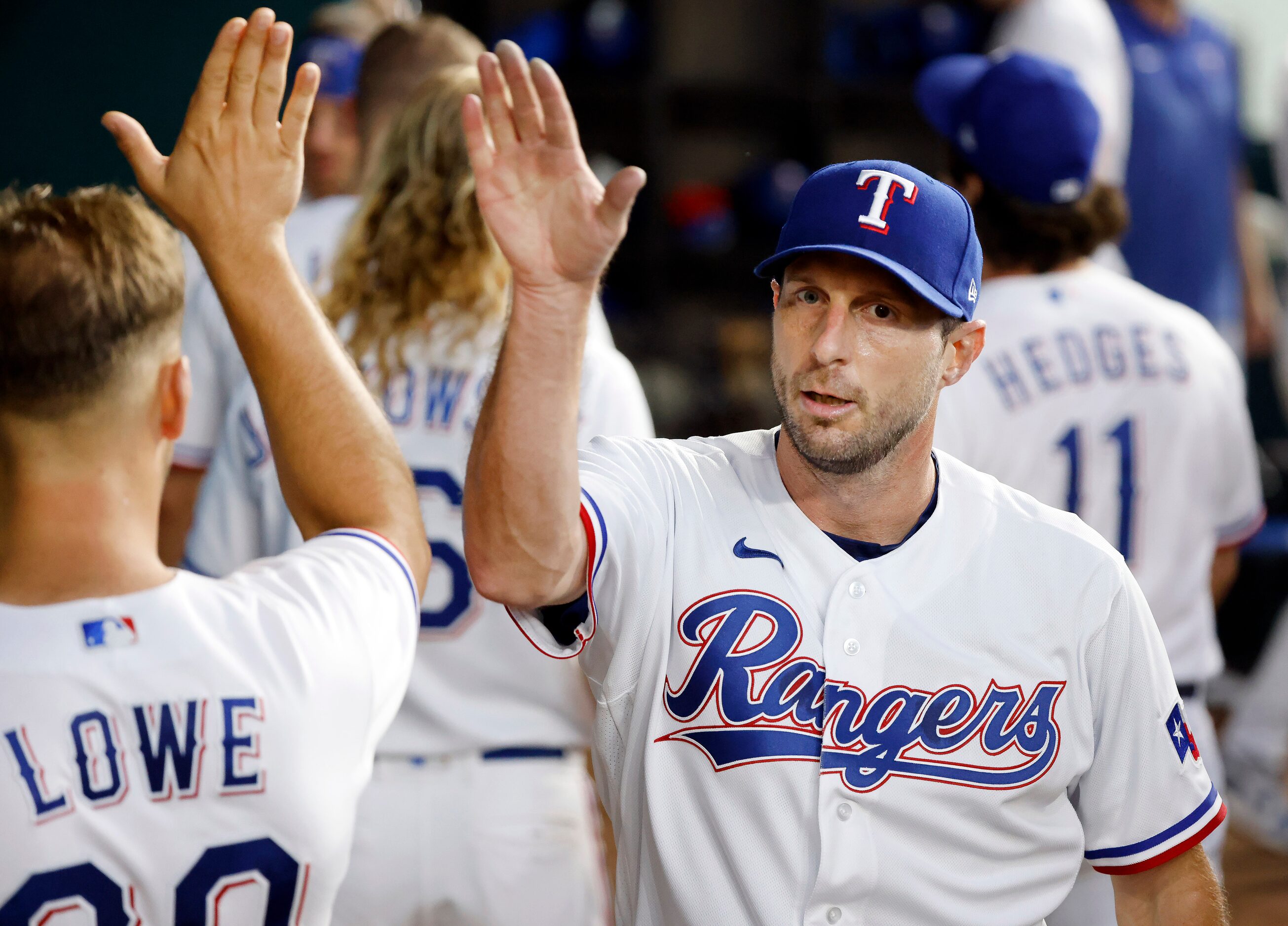 Texas Rangers starting pitcher Max Scherzer (31) delivers and receives fist bumps and...