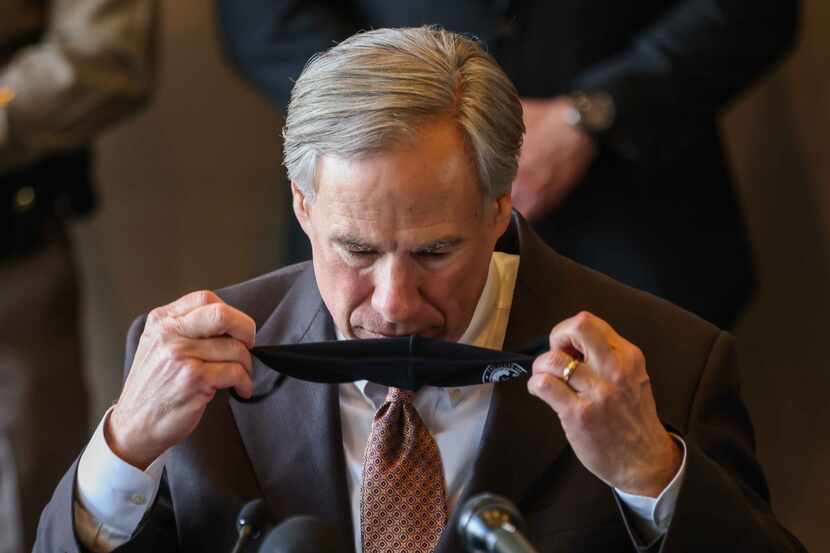 Gov. Greg Abbott takes off his face mask to start a press conference in Dallas, March 17, 2021.