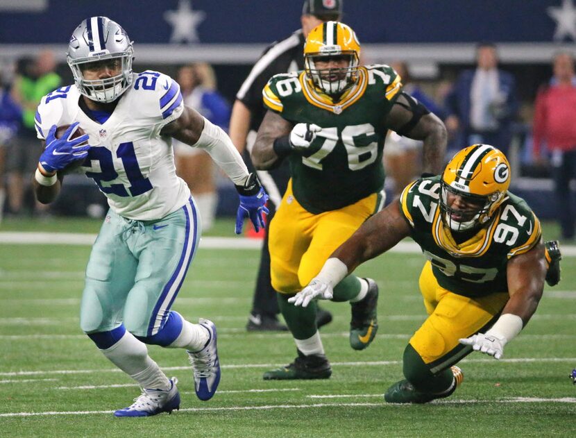 Dallas Cowboys running back Ezekiel Elliott (21) breaks through the line for good yardage in...