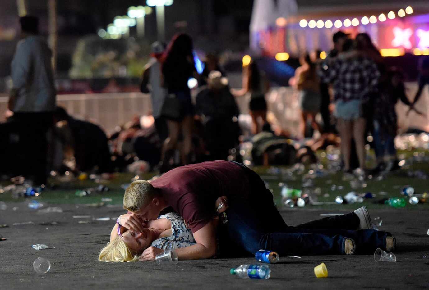 A man lays on top of a woman as others flee the Route 91 Harvest country music festival...