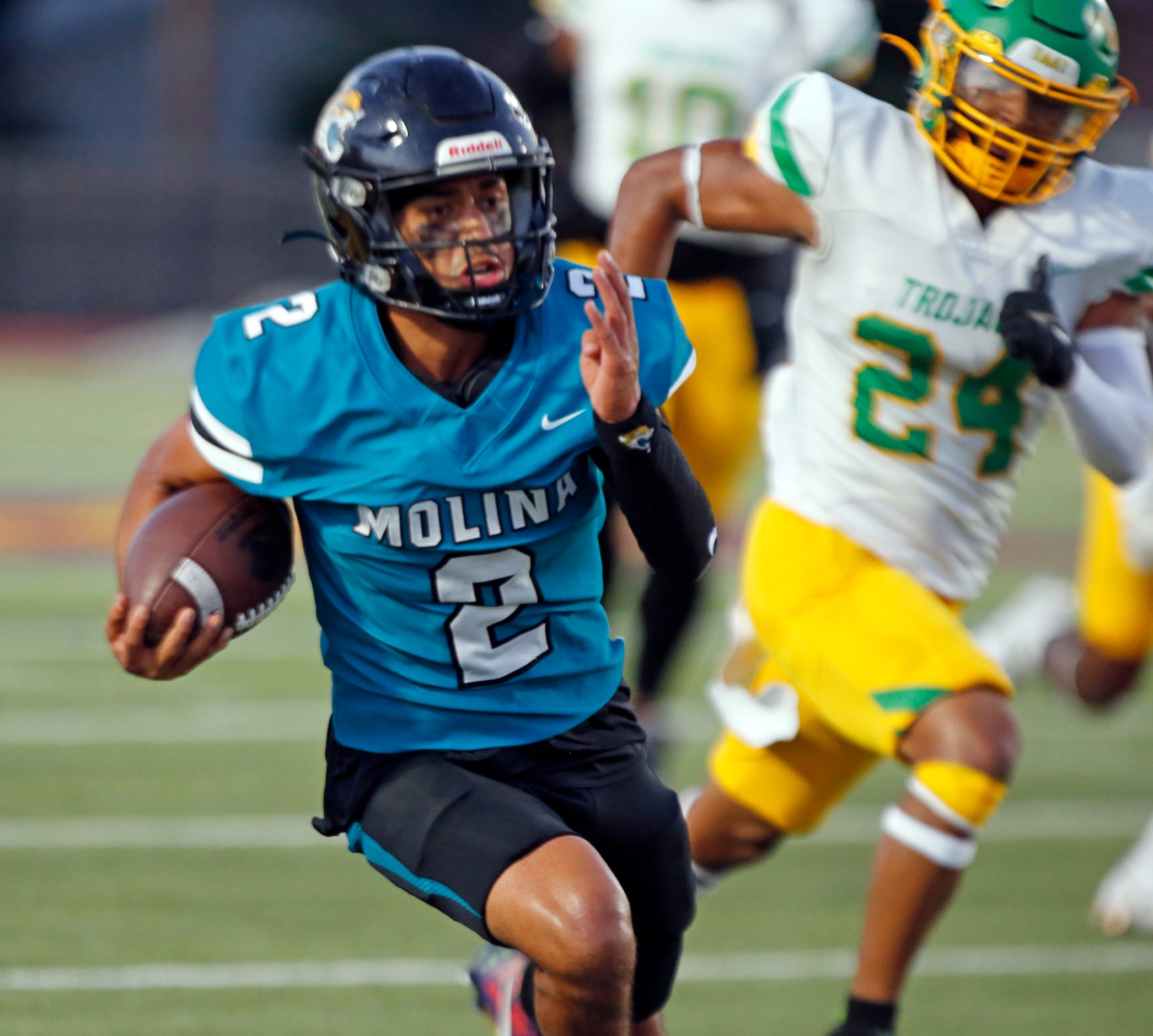 Molina high QB Adan Ochoa (2) scrambles thru the Carrollton Newman Smith high defense for a...