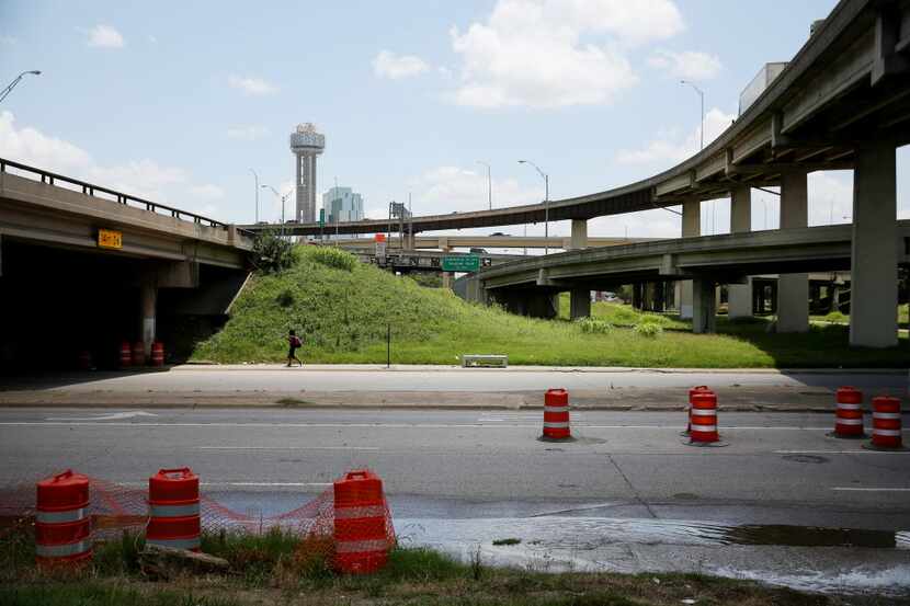 A pedestrian walks east underneath Interstate 35 along Continental Avenue, heading towards...