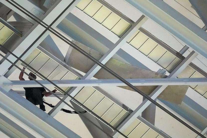 A stadium worker works to secure a loose piece of metal in the catwalk of AT&T Stadium after...