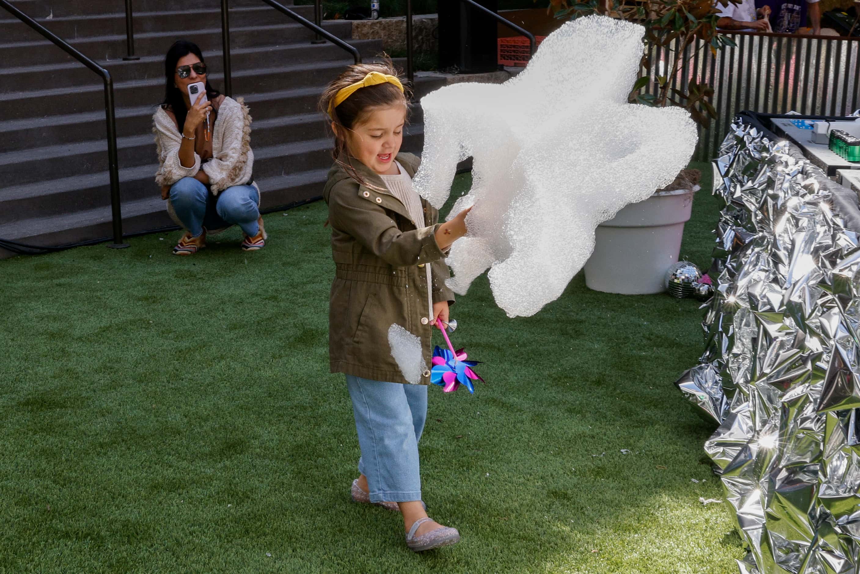 Olivia Martinez, 3, plays with bubbles as her mother Andi Martinez takes photos at the...