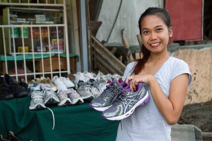 Young woman holds up shoes she is selling as part of her small business