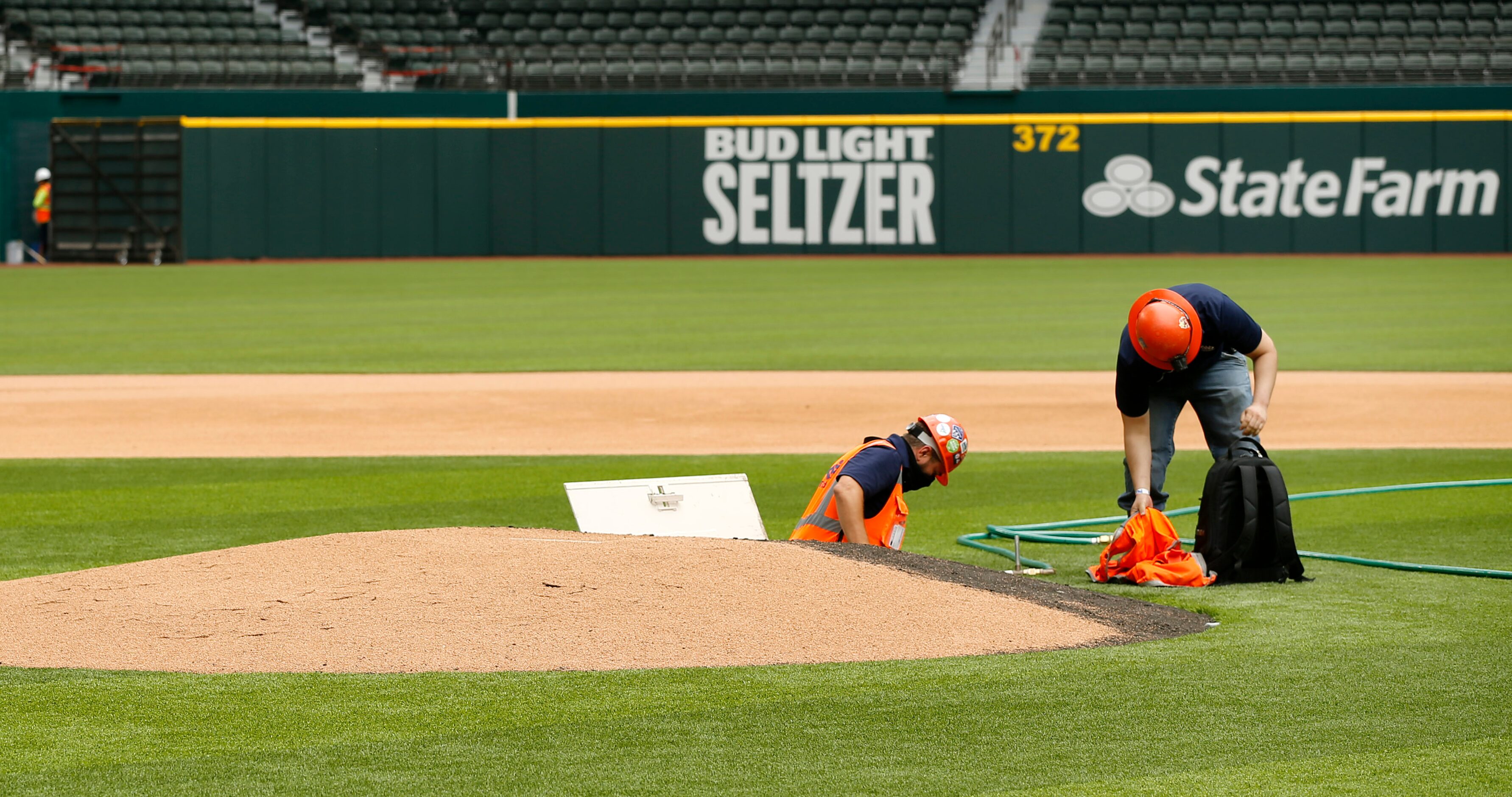 Construction workers climb out of the pitching mound at the newly completed Globe Life Field...