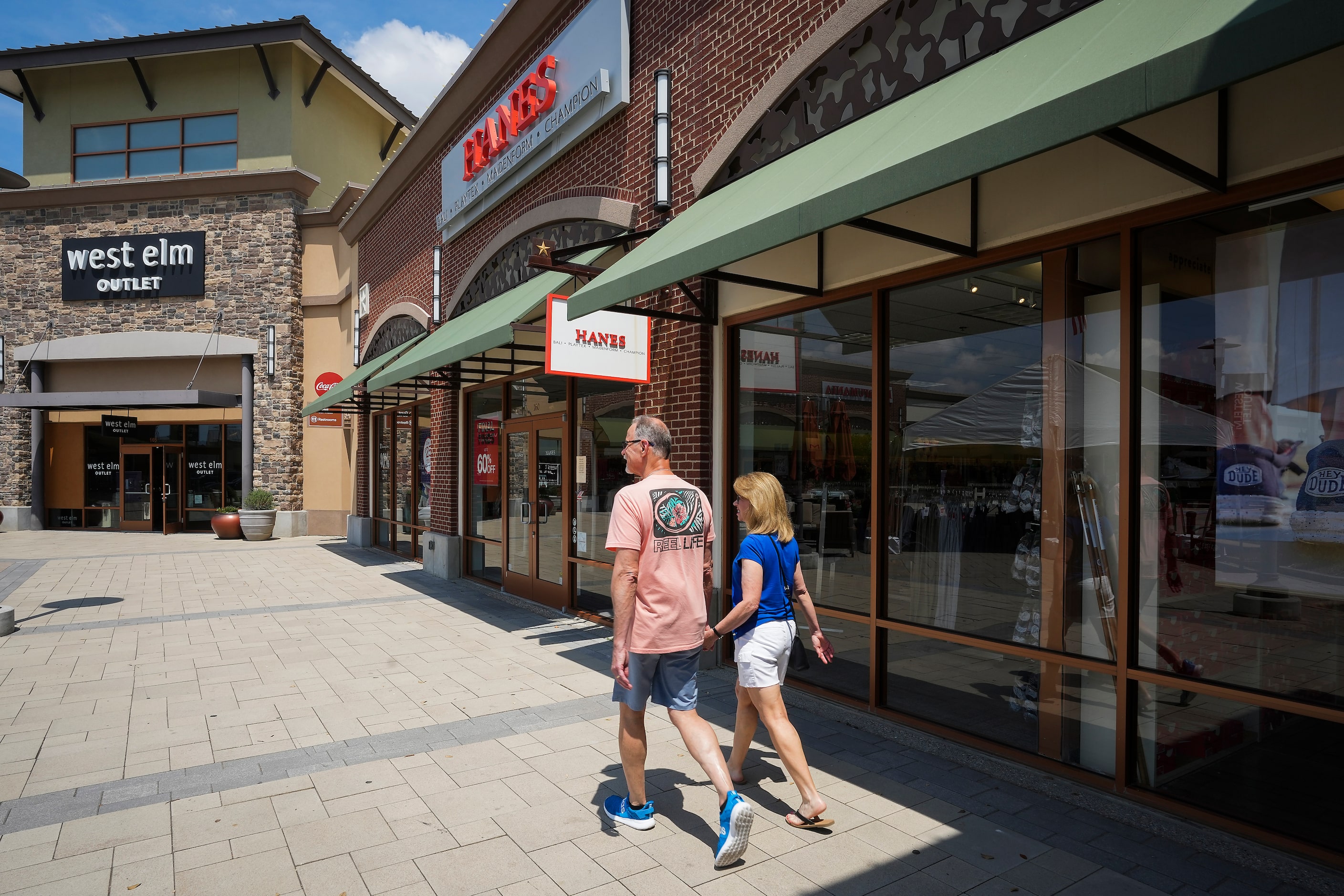 Kevin and Deb White of Prosper hold hands as they walk between stores at the Allen Premium...