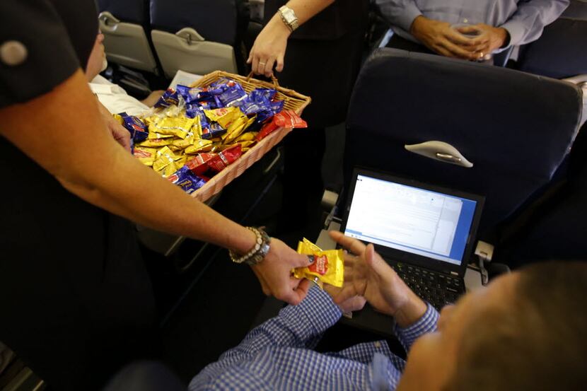 Southwest Airlines' Jenni Heikkinen hands out peanuts to passengers on Southwest Airlines...