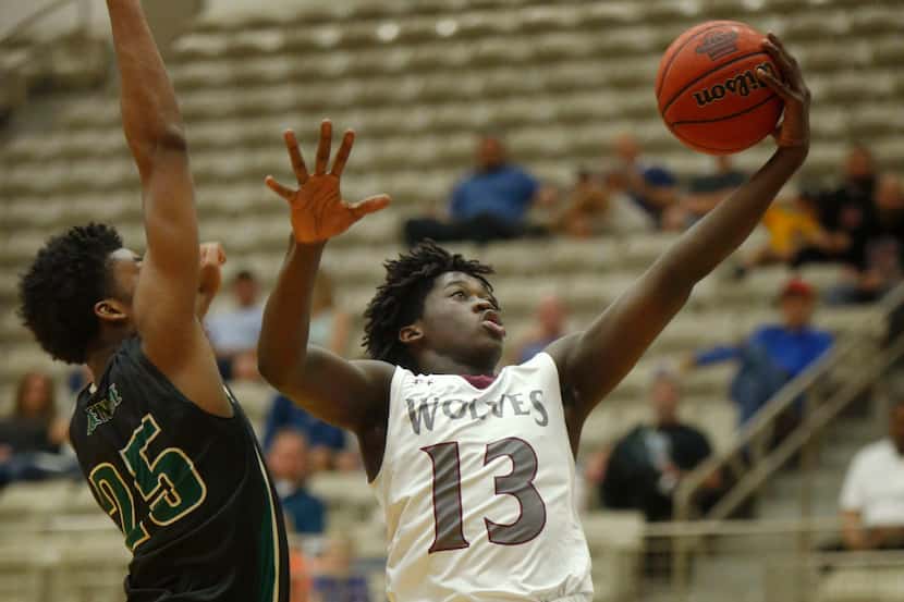 Mansfield Timberview's Isaac Likekele (13) lays up a shot against DeSoto's Xavier Ball (25)...