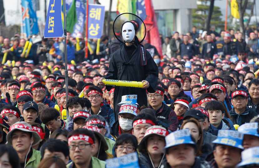 In this Saturday, Nov. 19, 2016 photo, a South Korean protester wearing a mask listens to a...
