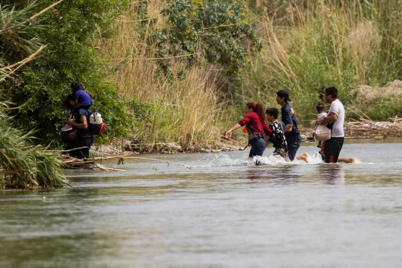 A Honduran woman leads her family while crossing the Rio Grande River from Mexico into the...