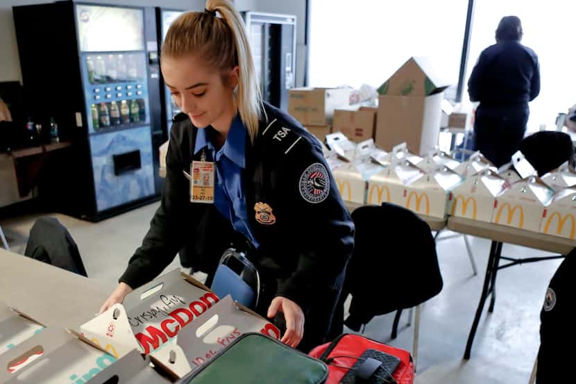 TSA officer Jenna Erickson, left, helps arrange boxes of meals at the TSA break room,...