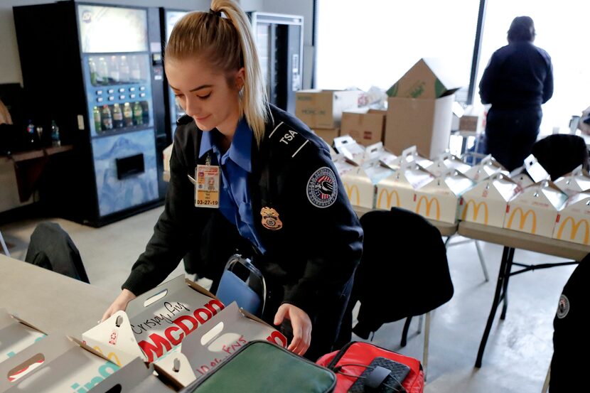 TSA officer Jenna Erickson, left, helps arrange boxes of meals at the TSA break room,...